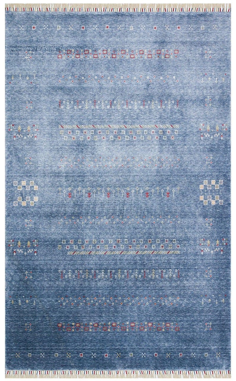 May include: A rectangular area rug in a deep blue hue with a distressed, mottled texture. The rug features horizontal rows of small, intricate geometric patterns in white, red, and yellow, finished with short, light-colored fringe at both ends.