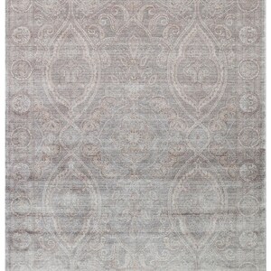 May include: A rectangular area rug featuring a faded, distressed aesthetic in shades of soft gray and muted taupe. The design displays an intricate, symmetrical pattern of ornate medallions and scrolling floral motifs enclosed within a wide border.