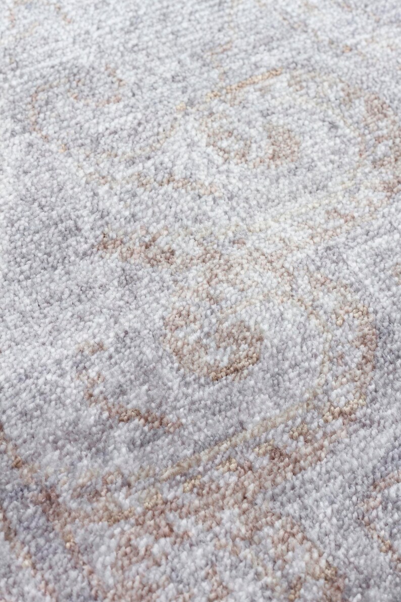 May include: A high-pile area rug featuring a soft, textured surface with a repeating damask-inspired pattern in shades of light gray, white, and muted beige. The dense, tufted fibers create a plush appearance with subtle color variations throughout.