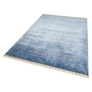 May include: A rectangular area rug featuring a gradient of blue tones, ranging from light to deep navy. The surface is decorated with horizontal rows of small, intricate geometric patterns in white and red, finished with cream-colored fringe.