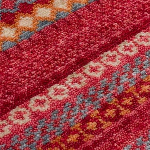May include: A textured rug featuring a vibrant red base with horizontal bands of intricate geometric patterns. The design incorporates repeating diamond and floral motifs in shades of cream, soft orange, and muted blue, creating a dense pile.