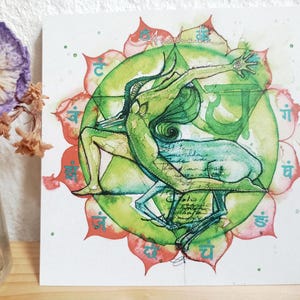 May include: Square art print with a watercolour illustration of a figure embracing a deer, set against a green and red lotus flower design. The artwork has a spiritual theme with script and symbols.