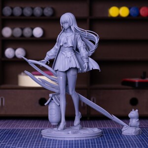 Puede incluir: Una figura gris claro de un personaje femenino con cabello largo, que lleva una falda corta, una chaqueta y botas. La figura est&aacute; de pie sobre una base circular con una estructura decorativa detr&aacute;s de ella. Una peque&ntilde;a figura de animal est&aacute; en el lado derecho.