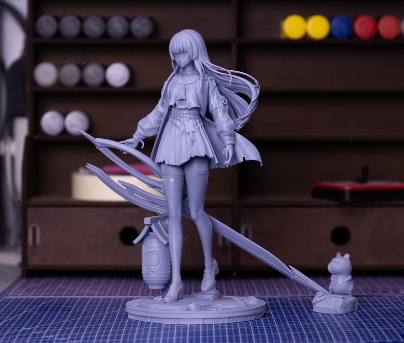Puede incluir: Una figura gris claro de un personaje femenino con cabello largo, que lleva una falda corta, una chaqueta y botas. La figura est&aacute; de pie sobre una base circular con una estructura decorativa detr&aacute;s de ella. Una peque&ntilde;a figura de animal est&aacute; en el lado derecho.