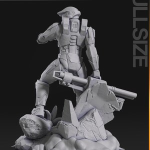 May include: A gray, full-size action figure of a futuristic soldier holding a large weapon, standing on a rocky base. The figure is detailed with armor and a helmet. The image includes the text "nomnom Figures TURNTABLE" and "FULLSIZE".