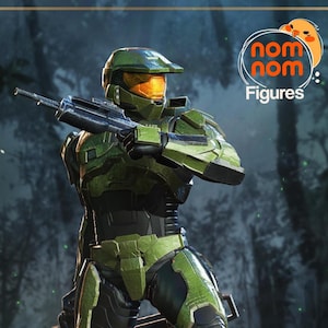 May include: A green and black action figure of a character in a futuristic military suit, holding a rifle. The figure has a helmet with an orange visor. The Nom Nom Figures logo is in the upper right corner.