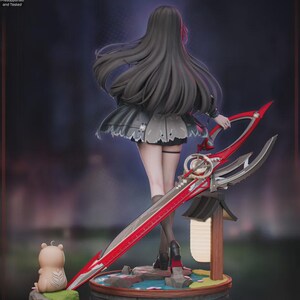 Puede incluir: Figura detallada de un personaje de "Wuthering Waves" con pelo largo negro y un vestido gris. La figura sostiene una gran espada roja y plateada. Tambi&eacute;n hay una peque&ntilde;a figura con forma de oso y una linterna japonesa en miniatura.