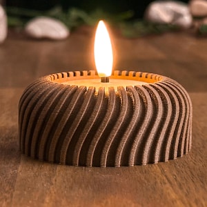 Könnte beinhalten: Ein brauner Kerzenhalter mit einem gewellten, strukturierten Design. Die Kerze ist angezündet und die Flamme ist sichtbar.