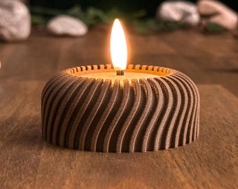 May include: A brown candle holder with a wavy, textured design. The candle is lit and the flame is visible.