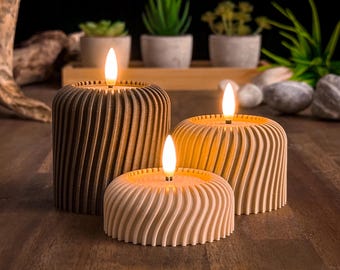 May include: Three decorative candles with a wood-like finish. The candles are lit and have a warm glow. The candles are on a wooden surface.