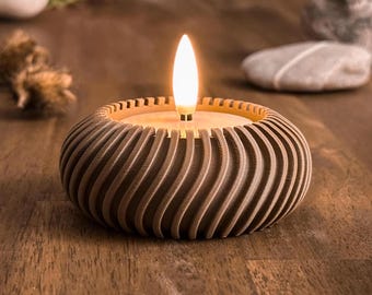 May include: A brown candle holder with a swirling, textured design. The holder has a small, white candle inside that is lit.