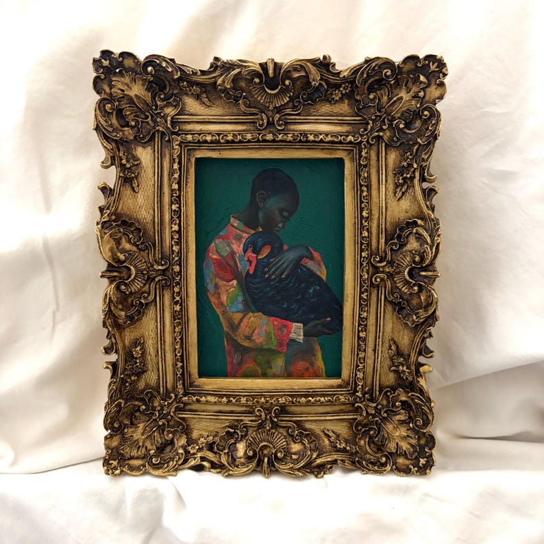 May include: A rectangular painting in an ornate, antique-style gold frame. The artwork depicts a person with short hair wearing a colorful, patterned shirt, holding a large black bird against a solid, deep teal background.