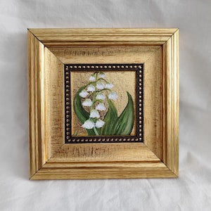 Peut inclure: Peinture carr&eacute;e encadr&eacute;e de fleurs de muguet. L'&oelig;uvre pr&eacute;sente des fleurs blanches en forme de clochettes et des feuilles vertes sur un fond dor&eacute;. Le cadre dor&eacute;, &agrave; l'aspect textur&eacute;, ajoute une touche d'&eacute;l&eacute;gance &agrave; cette &oelig;uvre florale.