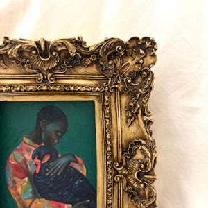 May include: An oil painting in a decorative gold frame featuring a person with dark skin wearing a colorful patterned shirt, holding a black swan against a solid dark teal background. The frame has ornate, raised floral and scroll carvings.
