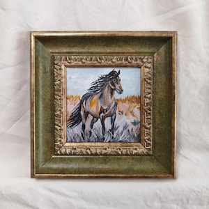 May include: A framed painting of a brown and black horse in a field of tall grass. The horse has a flowing mane and tail. The frame is a dark green with gold accents.
