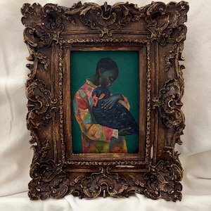 May include: An oil painting in a dark brown ornate frame featuring a person wearing a colorful patterned shirt holding a large black bird against a deep green background. The frame has intricate carved details with gold-toned highlights throughout.