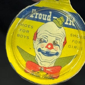 Könnte beinhalten: Vintage Proud-Fit Schuhknopfverpackung mit einem Clown-Gesicht, roter Fliege und grünem Hut. Die gelb-blaue Verpackung trägt die Aufschrift "SHOES FOR BOYS" und "SHOES FOR GIRLS".