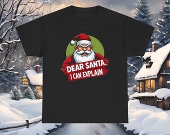 May include: Black t-shirt featuring a cartoon Santa Claus with an angry expression. The Santa graphic is set against a green circle and includes the text "DEAR SANTA, I CAN EXPLAIN" in red and white.