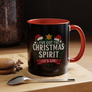 May include: Black ceramic mug with a red interior and handle. The mug features the text "I've Got The Christmas Spirit (It's Gin)" in white and green, with Santa hats and a star design.