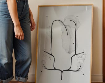 Pode incluir: Uma impressão de arte abstrata emoldurada com um design botânico em preto e branco. A obra de arte tem um estilo minimalista com linhas fluidas e formas orgânicas. A moldura é de cor madeira clara.