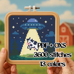 Puede incluir: Un bordado de punto de cruz en un aro de madera cuadrado representa un OVNI abduciendo una vaca. El fondo es un cielo nocturno con estrellas y una escena de granja. El texto "PDF + OXS", "3600 puntadas" y "13 colores" está incluido.