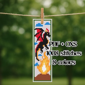 May include: A cross-stitch bookmark featuring a black dragon with red wings, flames, and clouds. The bookmark is held by a wooden clip. Text on the bookmark reads "PDF + OXS", "1008 stitches", and "8 colors".