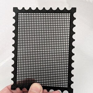 May include: A rectangular black grid panel with a scalloped, postage stamp-style edge. The object features a uniform, repeating square mesh pattern throughout its centre, framed by a solid border with rounded cutouts along all four sides.