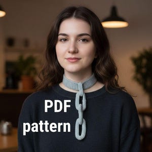 Op de afbeelding: Lichtblauwe gebreide sjaal met een kettingontwerp. De sjaal wordt om de nek gedragen en heeft een reeks verbonden lussen die naar beneden hangen. De tekst "PDF pattern" wordt in het wit op de afbeelding weergegeven. De persoon op de afbeelding draagt een donkerblauwe trui.