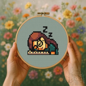 May include: A cross-stitch embroidery hoop with a pixelated design of a sleeping figure, complete with "Z" symbols above their head. The design is set on a pale blue fabric, framed by a wooden hoop. The background is a vibrant display of flowers.