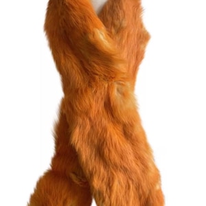 May include: A long, orange faux fur scarf with a fluffy texture. The scarf is wrapped around a white mannequin.