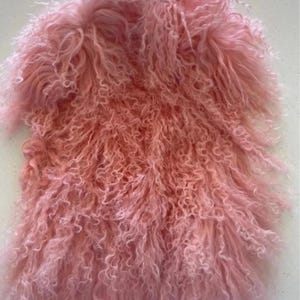 May include: A pink fluffy vest made of faux fur. The fur is long and curly, giving the vest a soft and cuddly look.
