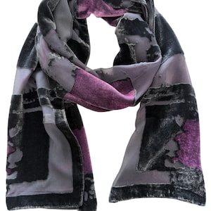 May include: A draped scarf in shades of gray, black, and purple. The scarf features a velvet texture with a patchwork design. The color palette includes dark gray, light gray, black, and a vibrant purple.