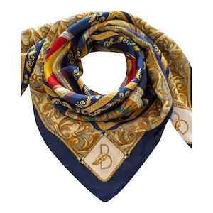 Puede incluir: Un pañuelo cuadrado de seda con un borde azul marino profundo y un diseño central de hojas de acanto doradas, patrones de cuerda y acentos rojos. Un parche blanco en forma de diamante muestra una letra B grande con un pequeño icono de hoja.