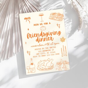 May include: Off-white invitation with orange illustrations and text. The text reads "Join us for a Friendsgiving dinner November 27th at 6pm". Includes illustrations of a pumpkin, turkey, wine, and other festive elements.