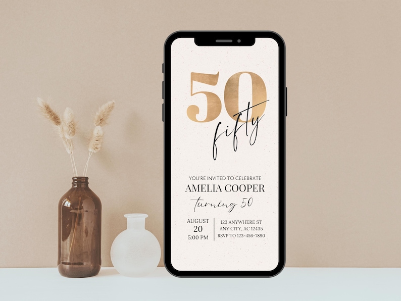 Puede incluir: Un tel&eacute;fono inteligente muestra una invitaci&oacute;n digital para el 50 cumplea&ntilde;os de Amelia Cooper. El dise&ntilde;o presenta n&uacute;meros y escritura dorados, con detalles del evento, como la fecha, la hora y el lugar. Un jarr&oacute;n marr&oacute;n con flores secas y un jarr&oacute;n blanco est&aacute;n en el fondo.