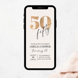 Puede incluir: Un tel&eacute;fono inteligente muestra una invitaci&oacute;n digital para el 50 cumplea&ntilde;os de Amelia Cooper. El dise&ntilde;o presenta n&uacute;meros y escritura dorados, con detalles del evento como fecha, hora y lugar.
