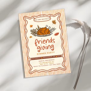 May include: A Friendsgiving dinner party invitation with a festive design. The invitation features a roasted turkey illustration, fall leaves, and the words "friends giving" in a playful font. The invitation includes the date, time, and location.