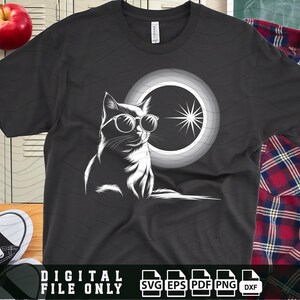 Może przedstawiać: Czarny t-shirt z białym nadrukiem przedstawiającym kota w okularach przeciwsłonecznych i półksiężycem za nim. Na dole koszulki znajduje się napis "DIGITAL FILE ONLY".