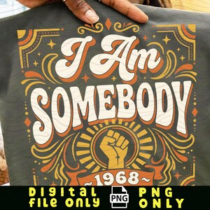 Può includere: Una maglietta grafica grigio scuro con le parole "I Am Somebody" in un font retrò, con un pugno alzato e l'anno "1968". Il design presenta accenti arancioni, gialli e bianchi. La parte inferiore dell'immagine recita "DIGITAL FILE ONLY PNG ONLY".