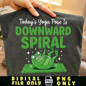 Może przedstawiać: Ciemnoszara koszulka z napisem "Today's Yoga Pose Is DOWNWARD SPIRAL" w kolorze białym i zielonym. Kreskówkowa żaba leży na zielonej macie do jogi. Na dole koszulki napis "DIGITAL FILE ONLY" i "PNG ONLY".