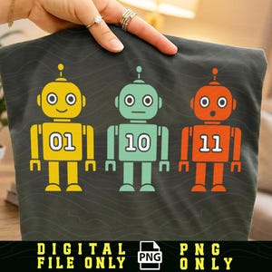 May include: A dark gray fabric featuring three colorful robot illustrations. The robots are yellow, teal, and orange, each with a different number on their chests: 01, 10, and 11. The words "DIGITAL FILE ONLY" and "PNG ONLY" are at the bottom.