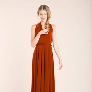 May include: A long, rust-coloured maxi dress with a halter neckline and a braided belt.
