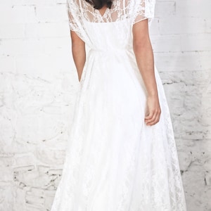 May include: A white lace maxi dress with a V-neckline and short sleeves. The dress is flowy and has a relaxed fit.
