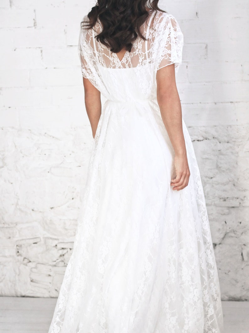 May include: A white lace maxi dress with a V-neckline and short sleeves. The dress is flowy and has a relaxed fit.