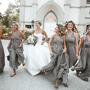 Beautiful group of bridesmaids running with the bride. The bridesmaids are wearing a long infinity taupe dress, all wrapped in different ways.