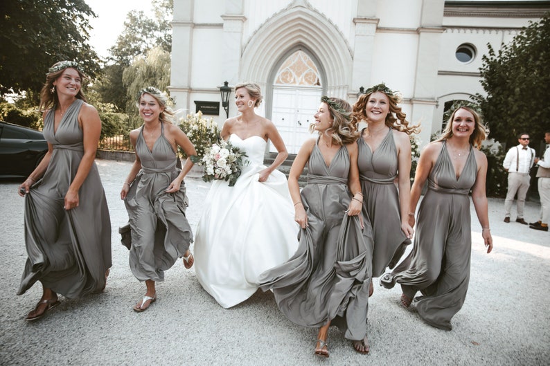 Beautiful group of bridesmaids running with the bride. The bridesmaids are wearing a long infinity taupe dress, all wrapped in different ways.