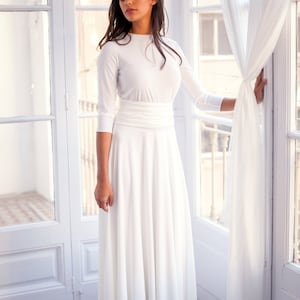 Woman wearing a winter wedding dress in ivory. The bridal gown is simple yet elegant, perfect for the modest