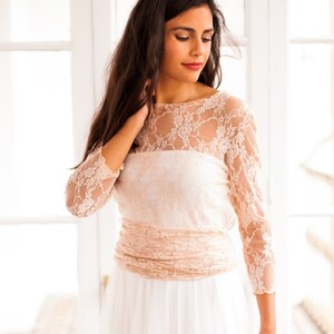 Model wearing wedding dresses. This is a romantic wedding dress. It's not ivory but pink, which is both alternative and very femenine. The bodice is a convertible wrap top.