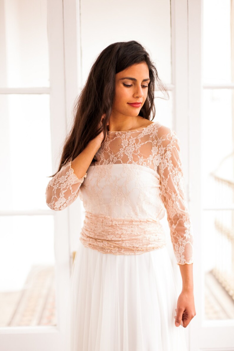 Model wearing wedding dresses. This is a romantic wedding dress. It's not ivory but pink, which is both alternative and very femenine. The bodice is a convertible wrap top.