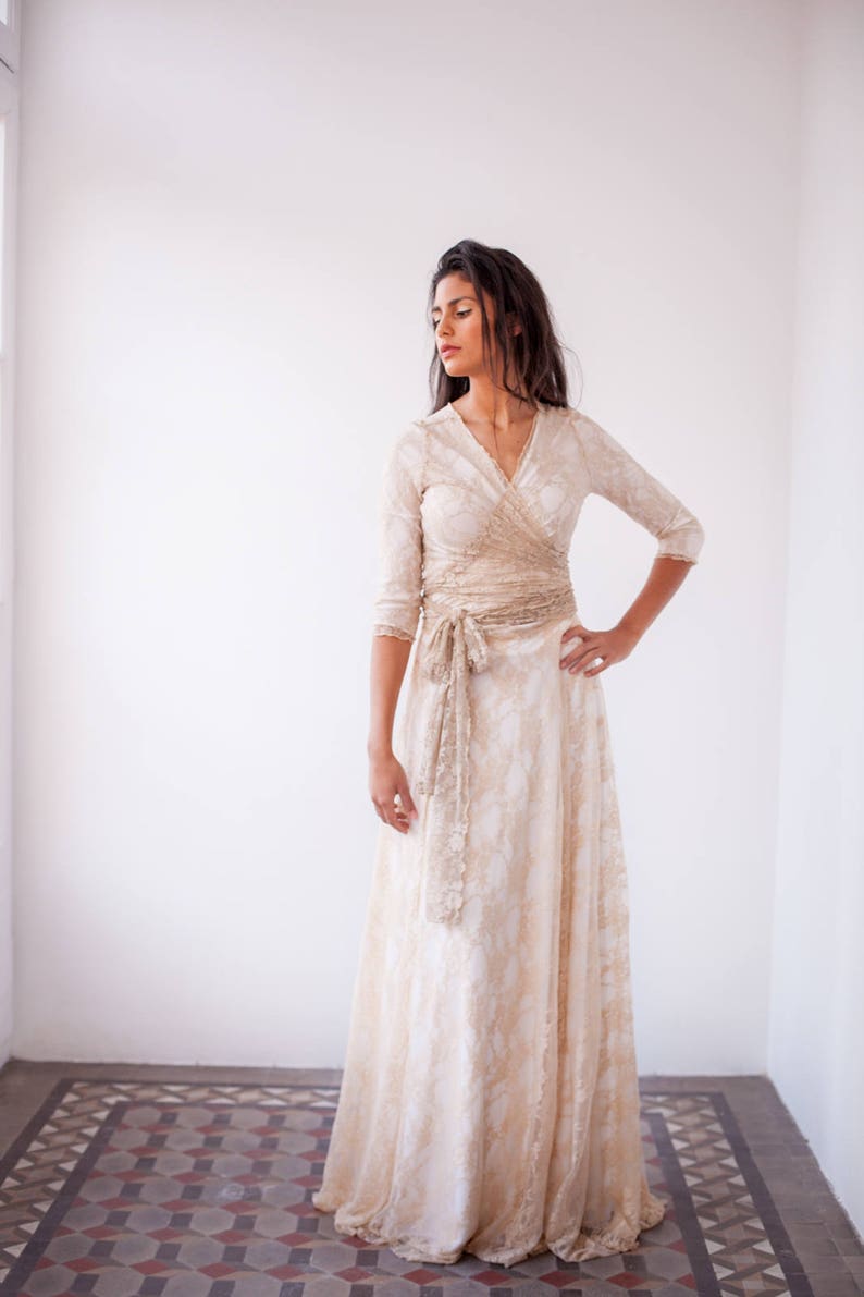 Woman looking at the left and with the hand in the waist wearing a boho wedding dress with sleeves